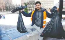  ??  ?? Akbar Ali from The Ahmadiyya Muslim Youth Associatio­n holds bags of trash collected by volunteers downtown on Wednesday.