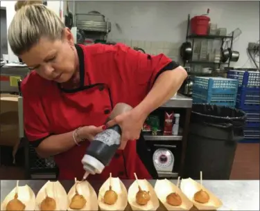  ?? JANET PODOLAK — THE NEWS-HERALD ?? Leanna Johnson, new chef de cuisine at Molinari’s, drizzles maple syrup on chicken and waffle lollipops, which lead the appetizer list on the new Comfort Kitchen menu.