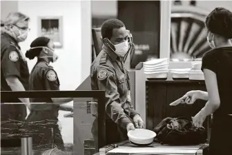  ?? Elaine Thompson / Associated Press ?? TSA officers wear protective masks at a security screening area at Seattle-Tacoma Internatio­nal Airport. Airlines say they’re stepping up security on flights to Washington.