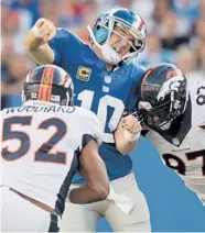  ?? | GETTY IMAGES ?? Wesley Woodyard and Malik Jackson of the Broncos make a sandwich out of Giants QB Eli Manning in the first half Sunday.