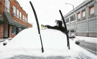  ?? Scott P. Yates / Associated Press ?? Joey Bell clears snow off his car Tuesday in Rockford, Ill. Many schools and businesses closed.
