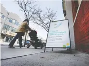  ?? PETER J THOMPSON / POSTMEDIA NEWS ?? A pedestrian walks past a vaccinatio­n sign-up notice outside of a pharmacy in Toronto on Tuesday. Canada will receive millions more doses in the coming months.