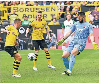  ?? FOTO: MARTIN MEISSNER/AP ?? Dortmunds Kapitän Marco Reus (Mitte) erwartet das Zuspiel von Paco Alcácer, der Augsburgs Torhüter umspielt. Aus der Situation entstand das 3:1 für Borussia Dortmund durch Reus.