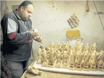  ??  ?? A worker carves figurines from olive wood.