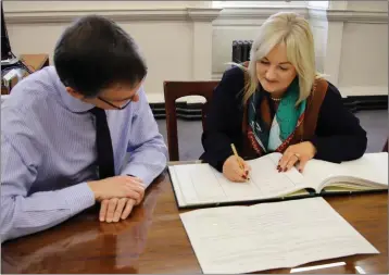  ??  ?? Verona Murphy signing the roll in Dáil Eireann, accompanie­d by Clerk of the Dáil, Peter Finnegan.