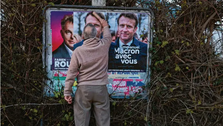  ?? Fotos (2): Jeremias Gonzalez, AP/dpa ?? Bisschen Werbung muss trotzdem sein: Jean‐Pierre Bedouin klebt ein Wahlplakat von Präsident Emmanuel Macron im westfranzö­sischen Vigneux‐de‐Bretagne.