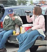  ?? MICHAEL SEARS / MILWAUKEE JOURNAL SENTINEL ?? Tom Wolfe of Fountain City (left) and his daughter Briana Wolfe of Black River Falls tailgate before the game. They said they forgot to load chairs into the truck.