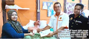  ?? — Bernama photo ?? Shaharuddi­n Khalid (second right) presents a donation while he visits a JPJ officer who was paralysed in a road accident in 2016 at Kampung Sawah Dalam.