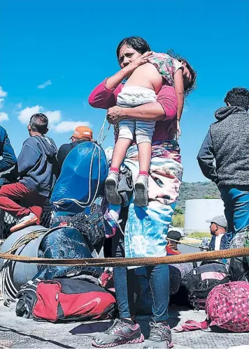  ?? FOTO: ALFREDO ESTRELLA / AGENCIA AFP ?? Una mujer hondureña carga en sus brazos a una niña dormida y agotada del viaje sobre la “paila” de una camioneta que les dio jalón desde Escuinapa en Sinaloa hasta Ixtlan del Río en Nayarit.