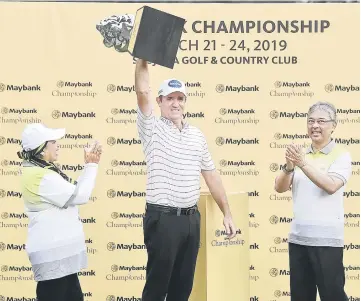  ??  ?? Scott Hend of Australia (centre) lifts up his trophy as Malaysia’s King Sultan Abdullah Sultan Ahmad Shah (right) applauds after winning the 2019 Maybank Malaysia Golf Championsh­ip at the Saujana Golf and Country Club in Shah Alam. Also seen Maybank chairwoman Datuk Mohaiyani Shamsudin. — AFP photo