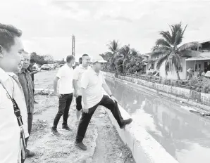  ?? ?? TELITI: Pang (kanan) bersama kakitangan agensi berkaitan turun padang meninjau perkembang­an projek pembinaan sistem parit besar di Kampung Assyakirin Bintulu.