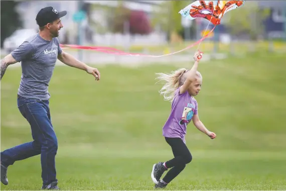  ?? JIM WELLS ?? Before the afternoon rain hit Calgary, Justin Gaulin flies a kite with his daughter Riley, 6, in Stanley Park on Sunday.