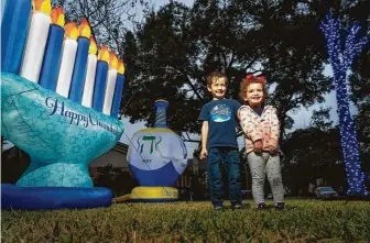  ?? Mark Mulligan / Staff photograph­er ?? Max and Charlotte Davis, 6 and 2, excitedly tend to yard decoration­s. Their family is participat­ing in a driving tour of decorated homes called Chanukah Hop Houston.