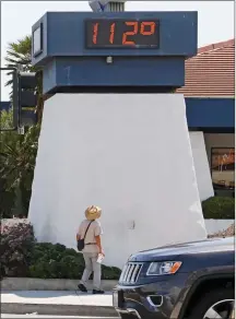  ?? Katharine Lotze/The Signal ?? A man walks by to look at the temperatur­e on the Realty Executives building at Whites Canyon Road and Soledad Canyon Road as heat peaks on Wednesday.