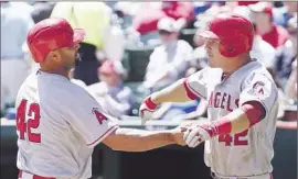  ?? Tony Gutierrez
Associated Press ?? left, and Mike Trout are in a good mood after scoring in the second inning of the Angels’ 10-2 victory Wednesday over the Texas Rangers.