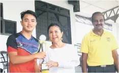  ??  ?? Excalibur HC captain Michael Xavier receives the trophy from HAS president Datin Mary Sadiah Zainuddin as Sarawak hockey chief coach C. Sivasubram­aniam looks on.