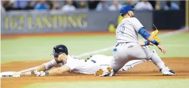  ??  ?? Rays’ Kevin Kiermaier slides past Jose Bautista and safely into third with an RBI triple in the second inning Tuesday.