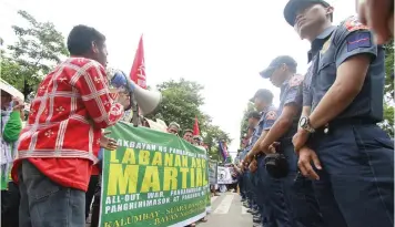  ??  ?? Policemen stand at ease while observing the Lumads and militant groups holding protest rally outside the Police Regional Office-7 yesterday.