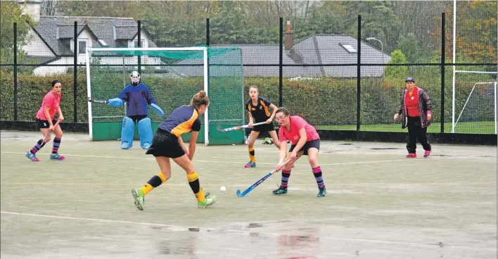  ?? 01_B43hockey0­1 ?? Arran’s Mia Walker blasts the ball away from her opponent. You can see the water lying on parts of the pitch