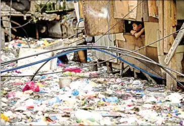  ?? NOEL CELIS/AFP ?? A boy looks out from a window of a house beside a garbage-filled creek on May 12 in Manila.