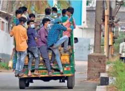  ??  ?? MIGRANT workers employed in factories travelling in a pick-up van at the PIPDIC industrial estate in Puducherry on May 4.