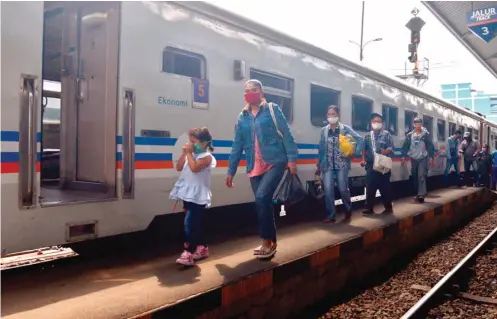  ?? AHMAD KHUSAINI/JAWA POS ?? WAJIB PAKAI MASKER: Para penumpang hendak memasuki gerbong KA lokal di Stasiun Pasar Turi, Surabaya, kemarin (11/6). Hari ini PT KAI kembali mengoperas­ikan KA reguler jarak menengah.