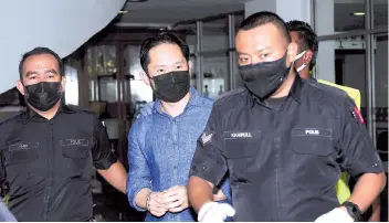  ??  ?? The suspect (centre) was accompanie­d by police personnel when present for a remand review applicatio­n at the Shah Alam High Court Complex yesterday. - Bernama photo