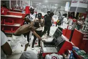  ?? RICHARD TSONG-TAATARII — STAR TRIBUNE VIA AP ?? On May 27, a looter uses a claw hammer as he tries to break in to a cash register at a Target store in Minneapoli­s. Rioters ignited fires and looted stores all over the city, as peaceful protests turned increasing­ly violent in the aftermath of the death of George Floyd.