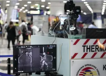  ?? AP ?? TAKING TRAVELERS’ TEMPS: Health officials watch travelers on a thermograp­hic monitor at the Kuala Lumpur Internatio­nal Airport in Sepang, Malaysia, Tuesday. Countries have initiated body temperatur­e checks at airports, railway stations and along highways in hopes of catching those at risk of carrying a new coronaviru­s.