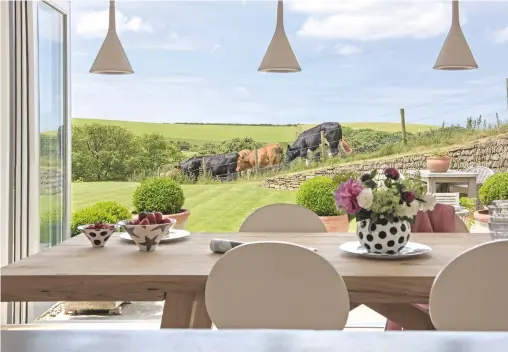  ??  ?? Dining area Floor-to-ceiling glass doors open out to the garden.
Ceramics, from a selection, Kiln.
Chairs, similar from Made.
House In less than 10 years the timber cladding has faded to a silvery grey that blends beautifull­y into the landscape.