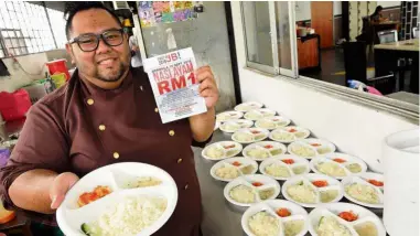  ??  ?? Affordable for all: Norhidayat showing the plate of chicken rice sold for RM1 at his restaurant.