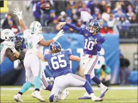  ?? Elsa / Getty Images ?? The Giants’ Eli Manning (10) passes under pressure from Christian Wilkins (94) of the Miami Dolphins on Sunday.