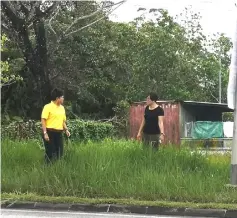  ??  ?? Tnay (left) inspects the area near a road in Batu Kawa that badly needs grass cutting service.