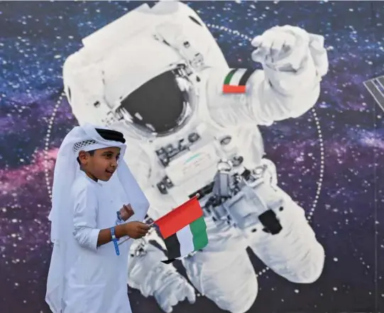  ??  ?? Opposite page: Hazza AlMansoori Above: A boy waves the UAE flag outside the Mohammed Bin Rashid Space Centre in Dubai