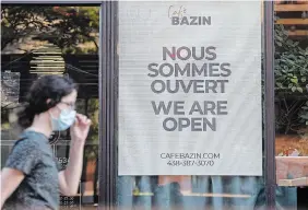  ?? GRAHAM HUGHES THE CANADIAN PRESS ?? A woman walks by a bilingual sign for a café in the city of Westmount on the Island of Montreal.