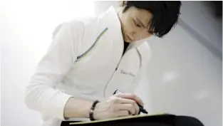  ?? ?? Top: Yuzuru Hanyu skates in Sendai on Aug. 10 during his first public practice session since turning pro; below left and right: Yuzuru Hanyu writes “Keep going!” on a shikishi paper board.