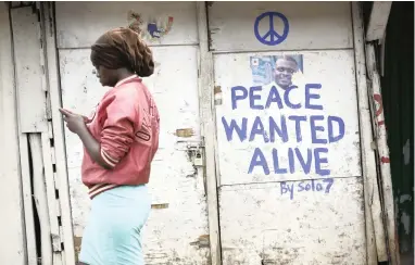  ?? PICTURE: EPA ?? POLITICAL SUPPORT: A woman walks past a shop with a message of peace painted by local street artist Solomon Muyundo, also known as Solo7, in Kibera slum, one of the opposition leader Raila Odinga’s stronghold­s in Kenya capital, Nairobi, on Monday.