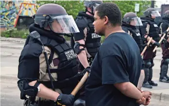  ??  ?? Un manifestan­te se coloca frente a un agente estatal de Minnesota