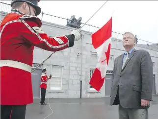  ?? ELLIOT FERGUSON ?? A flag owned by historian Arthur Milnes and his wife that once flew over the Peace Tower spent July 1 flying over Kingston at Fort Henry — raised by Cpl. MacGregor Van De Ven, left, and Pte. Chris Neely of the Fort Henry Guard as Milnes looks on.