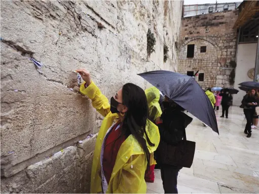  ?? (Ammar Awad/Reuters) ?? A MISS Universe contestant places a note in the Western Wall last year. The book describes how Jewish outreach activists often approach unaffiliat­ed persons during visits to the site.