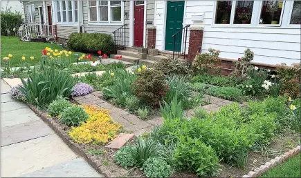 ?? JULIA RUBIN / AP ?? A rowhouse in New Rochelle, N.Y., has a front yard full of flowers and other plants, while neighborin­g houses have lawns of grass. Many people are converting parts of their lawns into planting beds for a variety of flowers, perennials and edible plants.