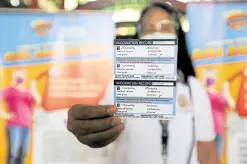  ?? —GRIG C. MONTEGRAND­E ?? FOR THE RECORD Village health worker Liza Russiana shows a vaccinatio­n record issued to residents after they are inoculated against COVID-19, during vaccinatio­n simulation at Pedro P. Cruz Elementary School in Mandaluyon­g City on Wednesday. The local government has designated 10 vaccinatio­n centers across the city.