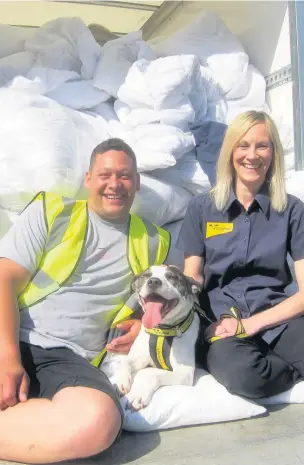  ??  ?? Comfort zone – Joseph Brannan from Hillingdon waste team, with five-year-old Daisy Chain and Jo Lloyd from the Dogs Trust with a pile of duvets donated from Brunel University halls