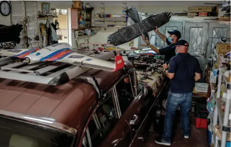  ??  ?? Ernesto Aragon (right) and Mykol Diaz (behind), members of Alasolucio­nes, place drones on a 1958 Ford Fairlane at their workshop.