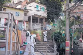  ?? LEO CORREA/ASSOCIATED PRESS ?? Volunteers spray disinfecta­nt in an alleyway to combat the spread of COVID-19 in the Babilonia slum of Rio de Janeiro on Sunday. The president of Brazil, Jair Bolsonaro, has tested positive for COVID-19