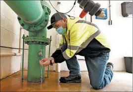  ??  ?? Joliet Chief Water Plant Operator Jay Rivera looks over flowing water from a faucet connected to pipe that carries thousands of gallons of water from multiple wells.