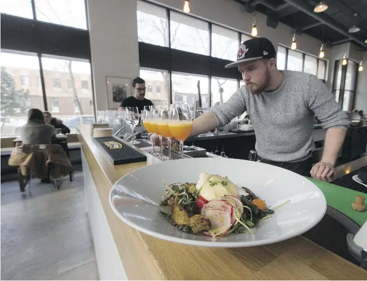  ?? GREG SOUTHAM ?? Operations manager Mike Forgie tees up mimosas made from freshly squeezed OJ while a breakfast bowl waits to be served at the District Cafe and Bakery at 10011 109 Street.