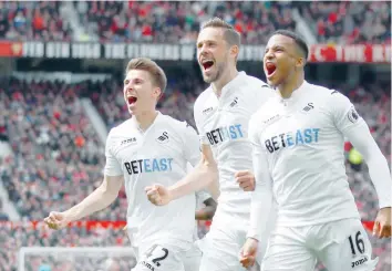  ?? — Reuters ?? Swansea City’s Gylfi Sigurdsson celebrates with Martin Olsson and Tom Carroll after scoring their first goal.