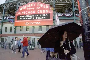  ?? AP Photo/Nam Y. Huh ?? Fans leave Wrigley Field after Game 4 of baseball's National League Division Series between the Chicago Cubs and the Washington Nationals was postponed until today because of rain Tuesday in Chicago.
