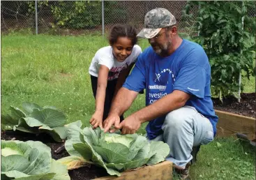  ?? Doug Walker / Rome News-Tribune ?? Akira Kessinger (left), 9, and Billy Ford marvel at the size of the cabbage growing in the Willingham Village garden.